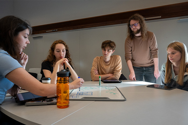 Students (left to right) Michaela Sewall, Yvette Gerber, Daniel Ruskin and Emily Zeiberg work together on a redistricting exercise as Ben Wormleighton observes. (Credit: Sid Hastings)
